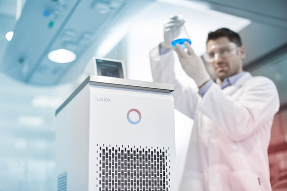 Un empleado en el laboratorio sujeta un matraz de reactivo con líquido de temperatura controlada.